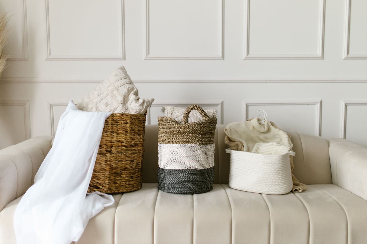 Stylish wicker baskets on a beige sofa in a modern, cozy living room environment.